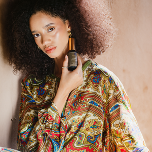 Model holding Skalli Essentials Cyperus Rotundus Oil, an organic Moroccan oil known for softening the skin and helping reduce unwanted hair regrowth over time.