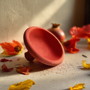 Handcrafted Moroccan clay pot surrounded by flowers, perfect for facial care and organic skincare rituals.