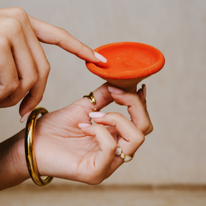 Moroccan clay pot being held for application, a natural skincare tool for facial care, offering deep nourishment with organic ingredients.