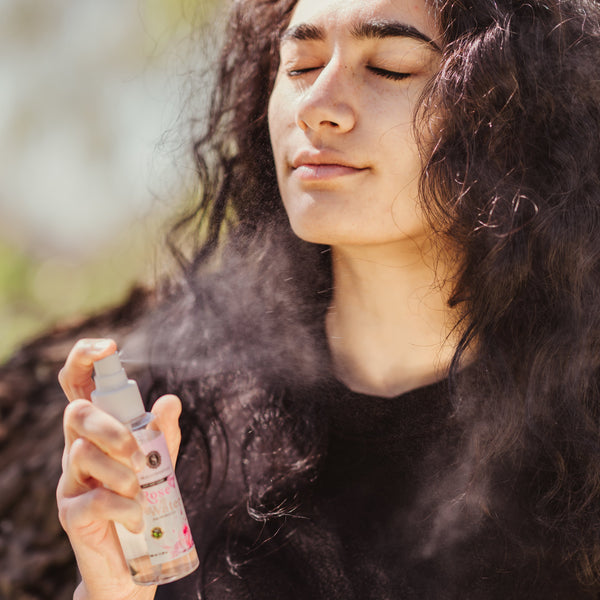 Model spraying Skalli Essentials Moroccan Rose Water onto her face, capturing the fine mist and skin refreshing benefits under natural light.